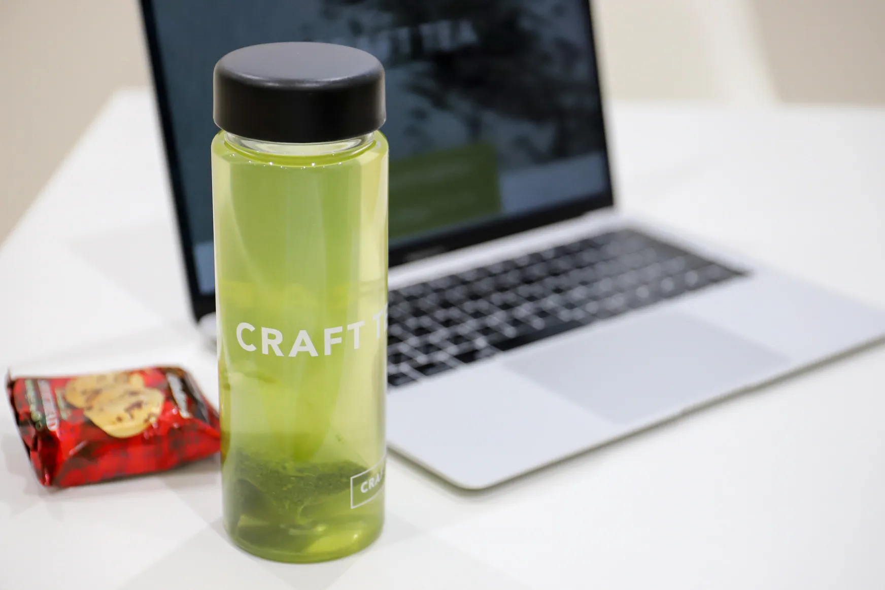 緑茶ボトルとクッキーの袋、奥にPC